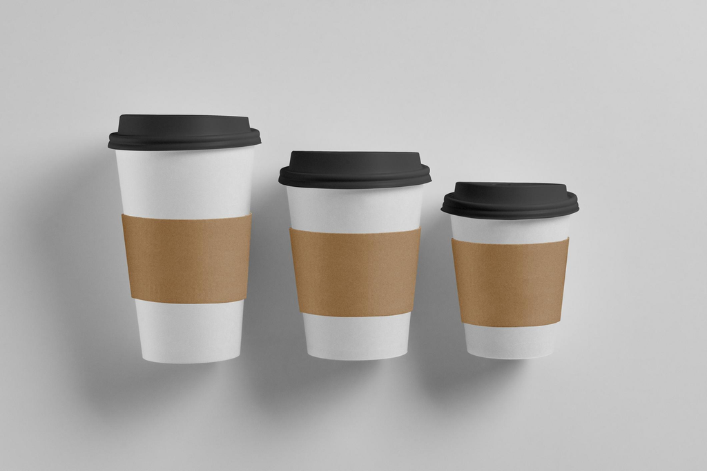 Kraft paper coffee cup sleeves fitted around white takeaway cups in different sizes